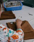 Coco Brown Hand Woven Linen Silk Blend Scarf being prepared by an artisan with a beautiful hand-stitched finish.