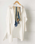 Oceana Beige Soft Linen Silk Handloom Scarf displayed with a white loose-fitting jacket on a wooden hanger.