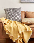 Oasis Charcoal Block Print Mulberry Silk Pillow Cover on a cozy couch with a yellow blanket.