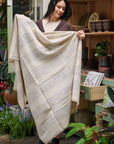 Silica Chalk Off White And Gray Stripes Pattern Soft Handwoven Merino Throw held by a woman in a botanical setting.