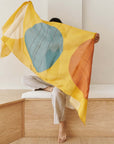 Cirq Sun Yellow Green Circle Pattern Hand Embroidered Linen Silk Handloom Scarf displayed by a person sitting on wooden steps.