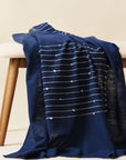Rosewood Indigo Hand Knotted Stripes Handloom Merino Throw draped over a wooden bench.