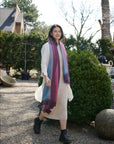 Iris Haze Blue Pink Cashmere Merino Handloom Scarf worn by a model in a garden setting.