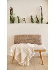 Sea Shell White Textured Checks Handloom Throw draped over a modern bench with decorative plant backdrop.