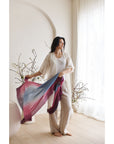 Iris Haze Blue Pink Cashmere Merino Handloom Scarf held by a model in a light-filled room.