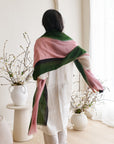 Model showcasing the Iris Kiwi Green Pink Cashmere Merino Handwoven Scarf elegantly styled with floral decor.