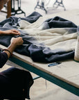 Artisan stitching the Ink Black White Ombre Textured Throw In Hand Spun Merino And Hand Stitched Hem.