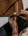 Hands examining the label of a Coco Brown Hand Woven Linen Silk Blend Scarf, showcasing artisan craftsmanship.