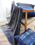 Alloy Dark Blue Stripes Pattern Soft Merino Linen Handloom Throw draped over a modern chair with decorative pillows.