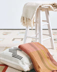 Sea Shell White Textured Checks Handloom Throw draped over a stool with decorative pillows on a patterned rug.