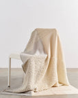 Butterscotch White Handloom Textured Plush Merino Throw draped over a chair showcasing its luxurious texture and design.