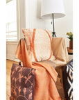 Chestnut Orange Cream Color Block Handwoven Merino Throw draped over a chair with decorative pillows in a cozy interior.