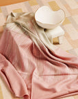 Chive Pink Green Ombre Handloom Merino Throw displayed elegantly with a ceramic bowl on a textured mat.