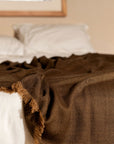 Hay Brown Twill Merino Handwoven Throw draped on a bed, showcasing its soft texture and subtle twill weave.