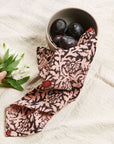 Hummus Floral Wax Block Printe Cotton Table Napkin( set of 4 ) elegantly draped with a bowl of plums and flowers.