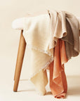 Chestnut Orange Cream Color Block Handwoven Merino Throw draped over a wooden bench.