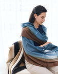 Mahogany Sky Brown Blue Ombre Linen Silk Handloom Scarf draped elegantly over a woman seated indoors.