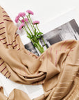 Maple Beige Handwoven Hand Embroidered Classic Scarf displayed with pink flowers on a book.