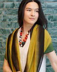 Mihika Red Silk Beaded Necklace Modern Artisanal worn with a stylish shawl against a green tiled background.