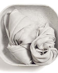 Pebble Light Gray Hand Woven Soft Linen Scarf displayed in a minimalist bowl, showcasing its elegant texture.