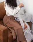 Pebble Light Gray Hand Woven Soft Linen Scarf draped elegantly over a person sitting on a brown couch.