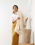 A woman draped in the Sea Shell White Textured Checks Handloom Throw, showcasing its exquisite texture and design.