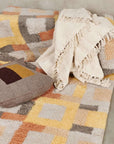 Sea Shell White Textured Checks Handloom Throw draped over a colorful geometric patterned sofa with a matching cushion.