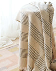 Silica Chalk Off White And Gray Stripes Pattern Soft Handwoven Merino Throw draped over a chair in a cozy setting.