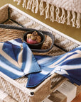 Tisa Indigo Hand Crafted Shibori Print Cotton Table Napkin set of 4 displayed on a woven tray with decorative items.