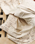 Unah Brown Fully Hand Embroidered Throw Handloom Organic Cotton Throw draped over a textured rug.