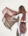Auro Cinnabar Handwoven Earthy Rust Maroon Linen Scarf being elegantly worn by a woman against a plain background.