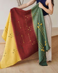 Avocado Green Multi Color Warm Hues Hand Woven Hand Knotted Textured Merino Throw draped over a person's arm in a cozy setting.