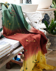 Avocado Green Multi Color Warm Hues Hand Woven Hand Knotted Textured Merino Throw draped over a chair in a cozy setting.