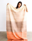 Woman holding a Chestnut Orange Cream Color Block Handwoven Merino Throw, showcasing its unique colors and craftsmanship.