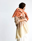 Woman draped in Chestnut Orange Cream Color Block Handwoven Merino Throw, showcasing unique handwoven craftsmanship.