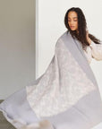 Model draped in a Flo Gray Textured Handloom Merino Throw showcasing its luxurious design and craftsmanship.