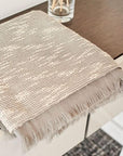 Flo Gray Textured Handloom Merino Throw displayed on a wooden surface, showcasing its luxurious design and craftsmanship.