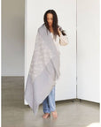 Flo Gray Textured Handloom Merino Throw draped elegantly by a woman in a spacious room.
