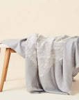 Flo Gray Textured Handloom Merino Throw draped over a wooden chair, showcasing luxury craftsmanship.
