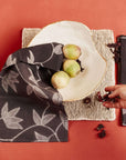 Folio Black Handcrafted Shibori Print Cotton Table Napkins ( set of 4 ) displayed with a bowl and fruit on a textured surface.