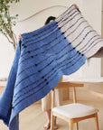Hand Knotted Merino Textured Mari Throw Blanket in Blue Gray displayed elegantly by a person in a minimalist setting.