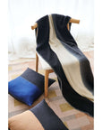 Ink Black White Ombre Textured Throw In Hand Spun Merino And Hand Stitched Hem draped over a chair with pillows.