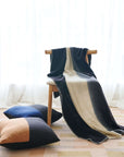 Ink Black White Ombre Textured Throw In Hand Spun Merino And Hand Stitched Hem draped over a chair with decorative pillows.