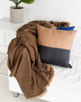 Kala Black & Gold Color Block Mulberry Silk Square Pillow with a cozy blanket on a modern sofa.