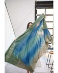 A woman showcasing the Lake Moss Handwoven Merino Throw Blanket in serene shades of blue and green.
