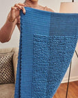 Macaroon Midnight Dark Blue Textured Merino Handloom Throw held by a woman showcasing its unique texture and color.
