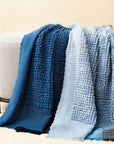 Macaroon Midnight Dark Blue Textured Merino Handloom Throw draped elegantly over a light-colored couch.