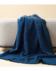 Macaroon Midnight Dark Blue Textured Merino Handloom Throw draped over a modern sofa in a cozy setting.