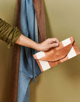 Person holding Melo Gold Mulberry Silk Shibori Hand Crafted Envelope Pouch against a green background.