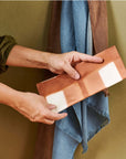 Melo Gold Mulberry Silk Shibori Hand Crafted Envelope Pouch being held by a person, showcasing its unique design.